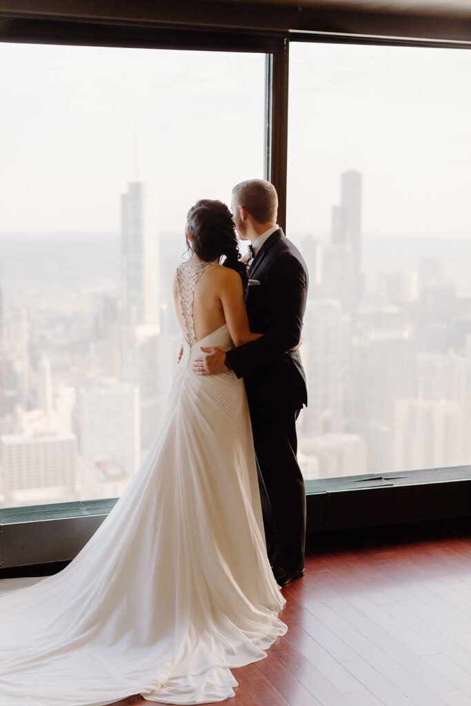 Bride and Groom with the city scape of Chicago behind them from high up at the Signature Room at the 95th