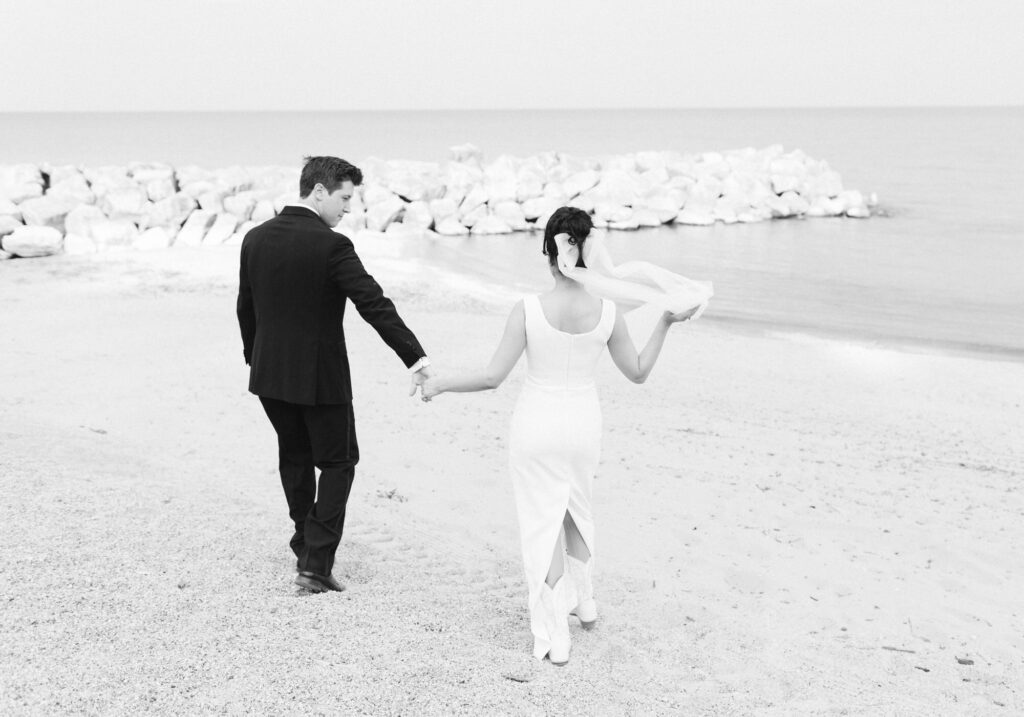 Groom leading Bride walking down the beach at Rosewood Beach in Highland Park
