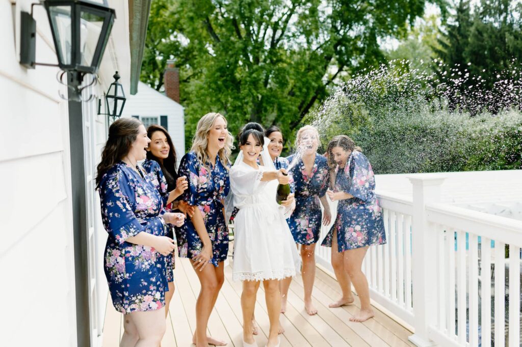 Bride and Bridesmaids spraying champagne on a deck outside