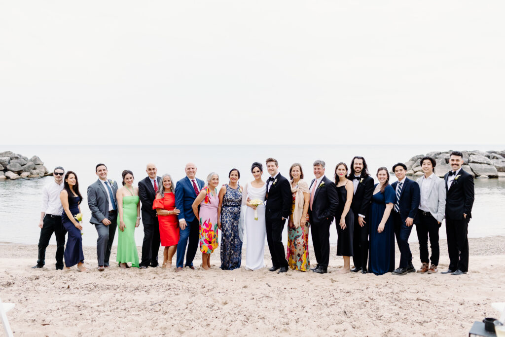 Portrait of bride and Groom and family on  Rosewood Beach in Highland Park standing on the sand laughing at the camera