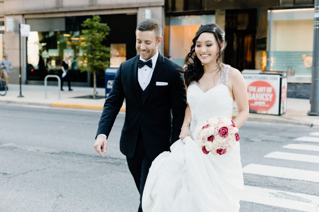 Bride and groom walking across a city street on the way to the Signature Room at the 95th