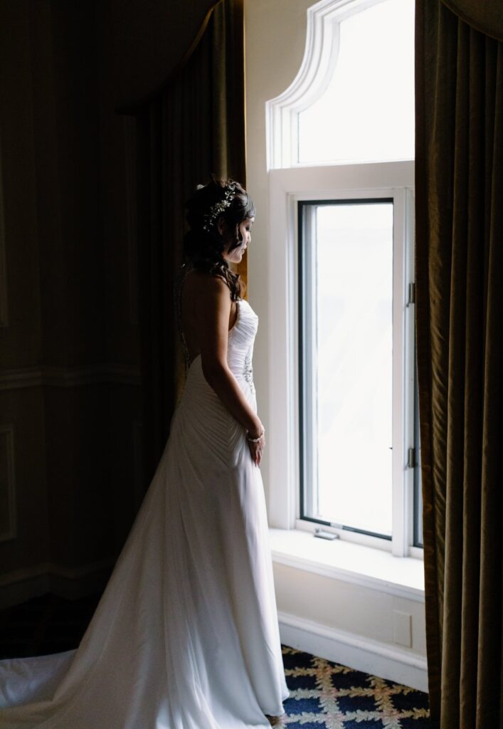 Bride standing in front of a window as light falls on her