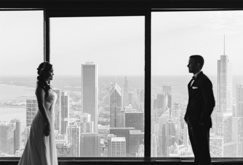 Bride and groom looking at each other in front of a large window showing the Chicago city scape at the Signature Room