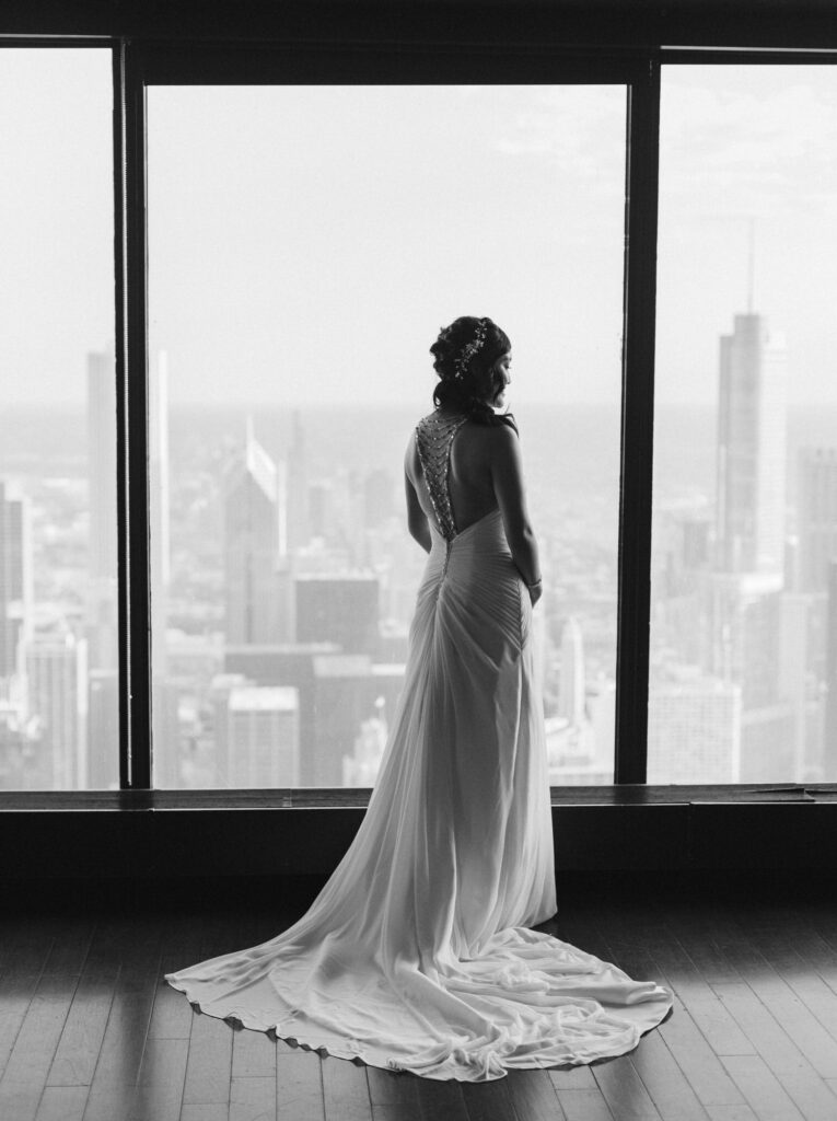 Bride standing in front of a large window at the Signature Room at the 95th viewing the Chicago city scape