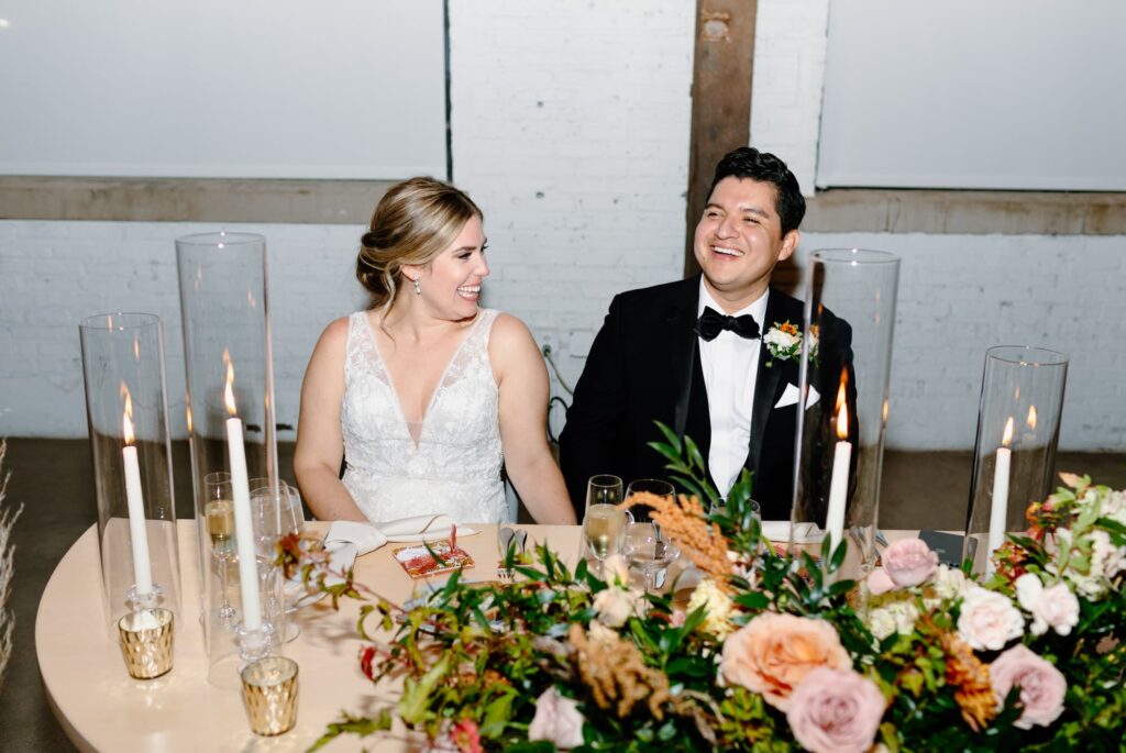 Bride and Groom at sweetheart table smiling during toasts
