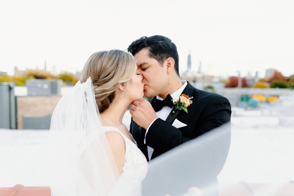 Groom kissing bride with veil flowing around them