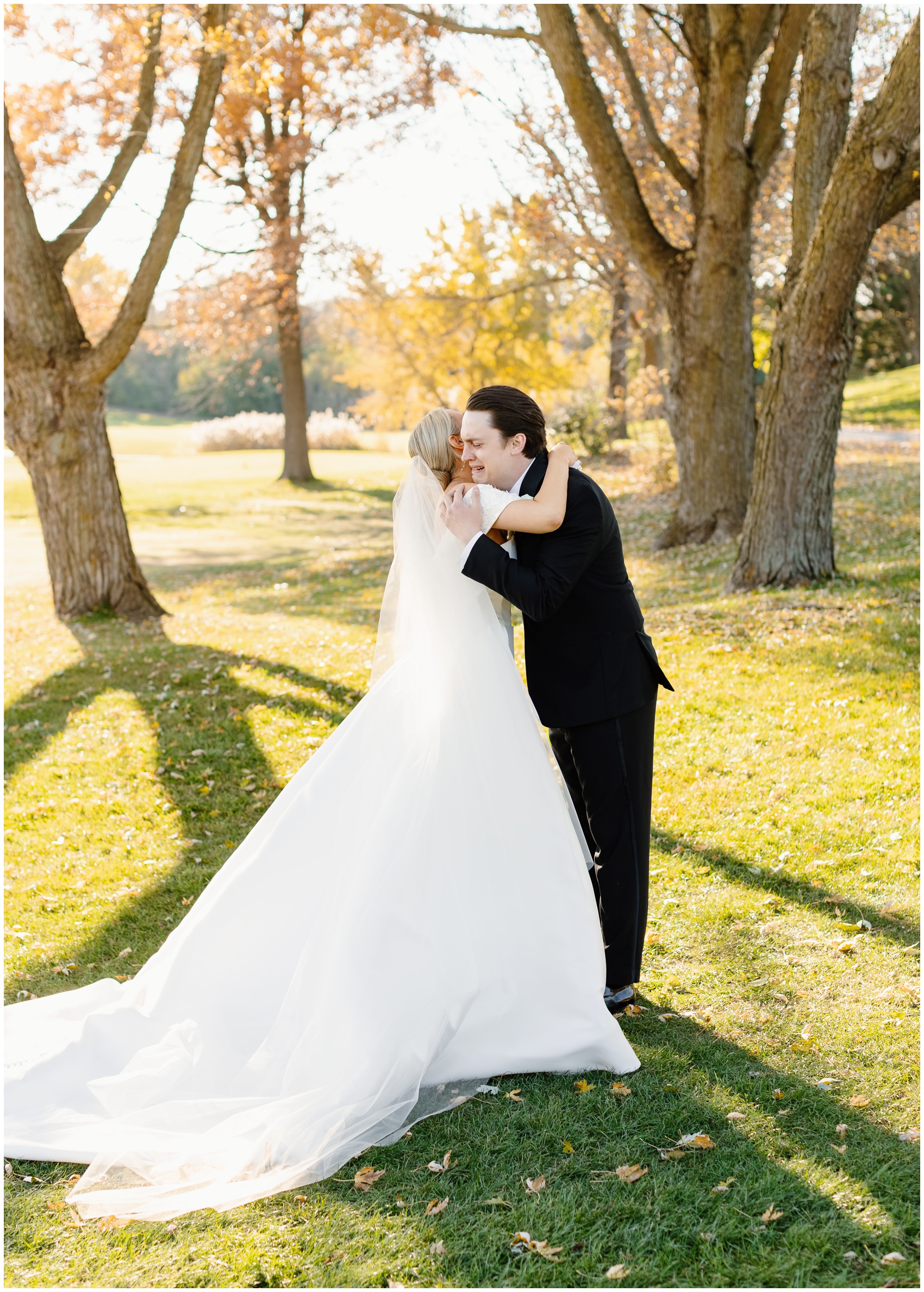 A groom cries during his first look in a black suit in a park lawn at sunset