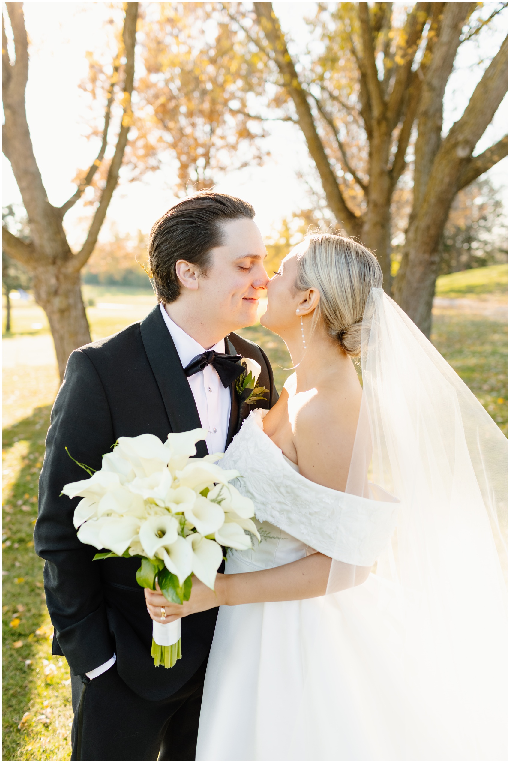 A bride and groom lean in for a kiss while standing in a lawn at their Hyatt Lodge Oak Brook Wedding at sunset