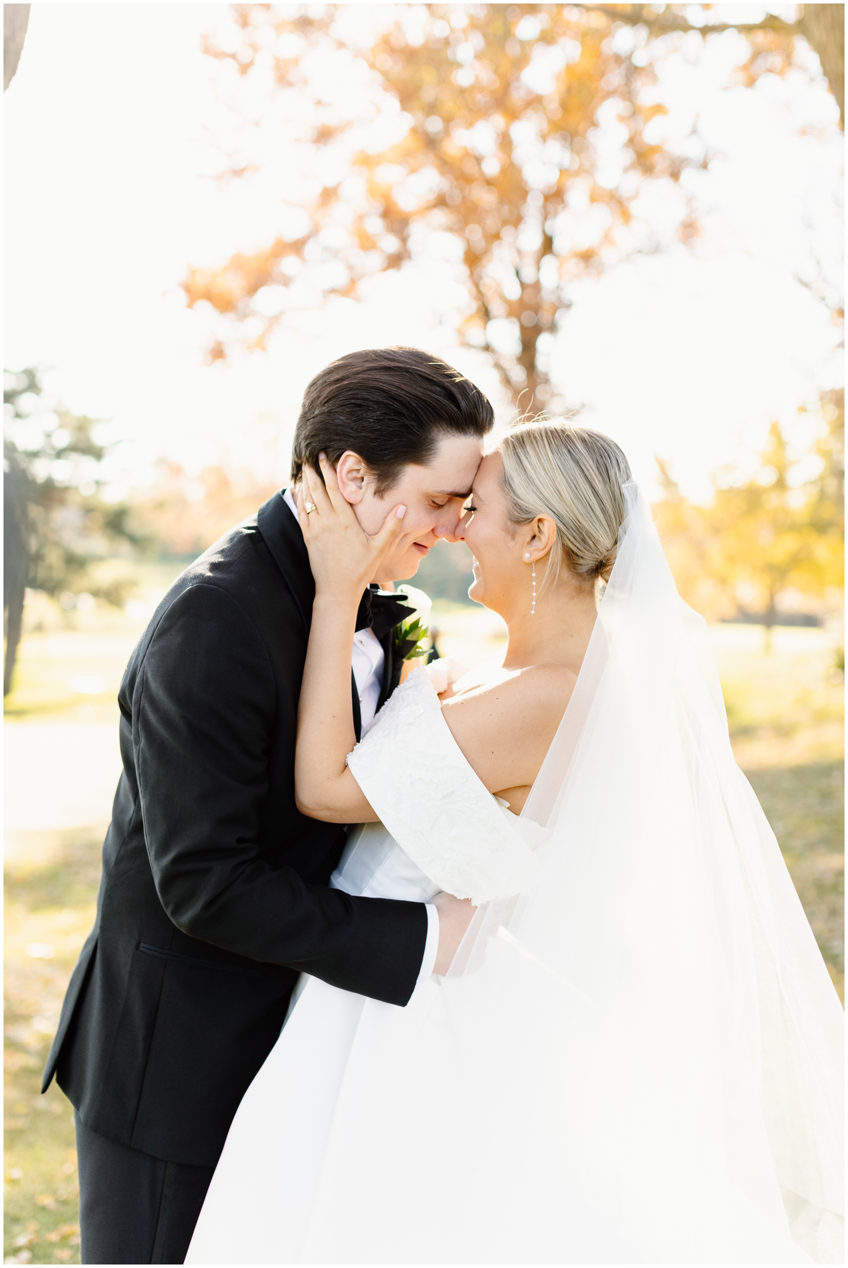 A bride and groom laugh while touching foreheads under a tree at sunset at their Hyatt Lodge Oak Brook Wedding