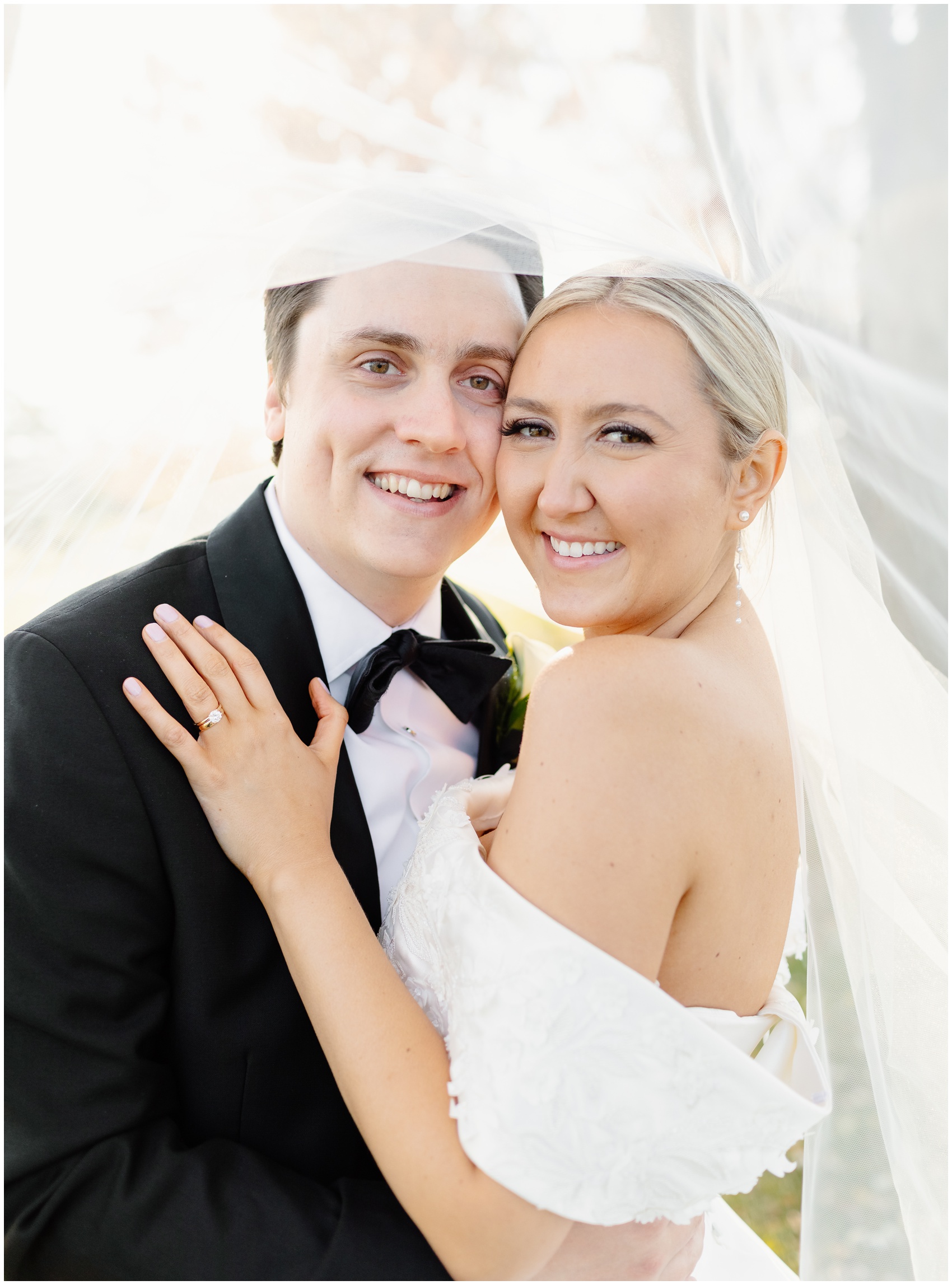 Newlyweds stand cheek to cheek under the veil