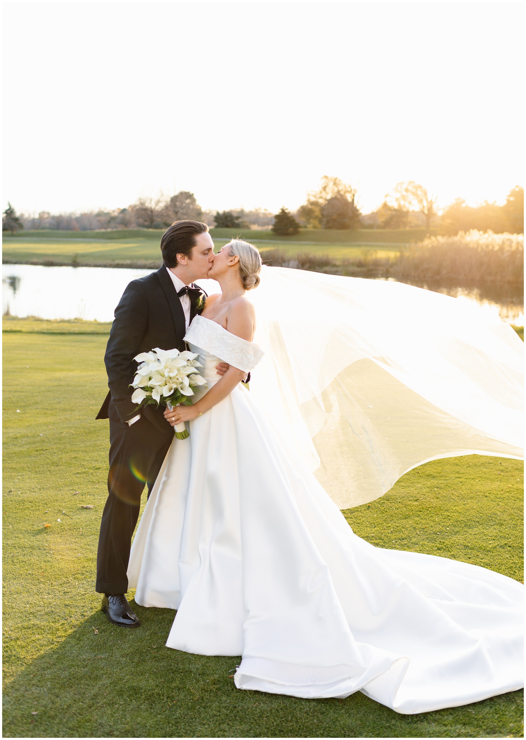 Newlyweds kiss while the veil flows in the wind on a golf green at their Hyatt Lodge Oak Brook Wedding