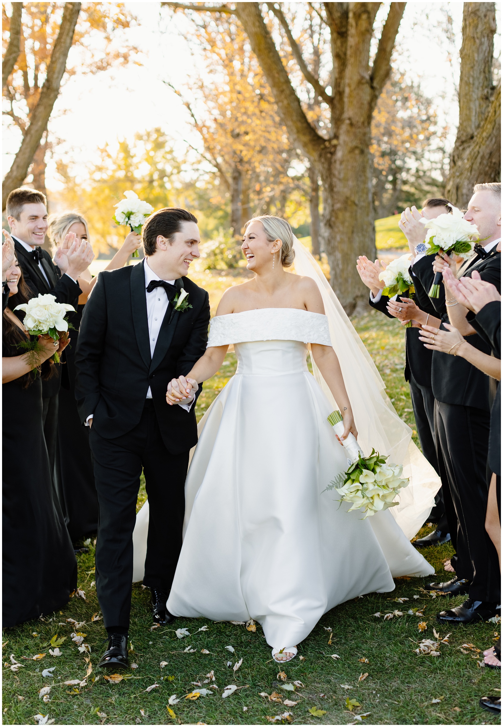 Newlyweds laugh at each other while holding hands and walking between their cheering party at their Hyatt Lodge Oak Brook Wedding