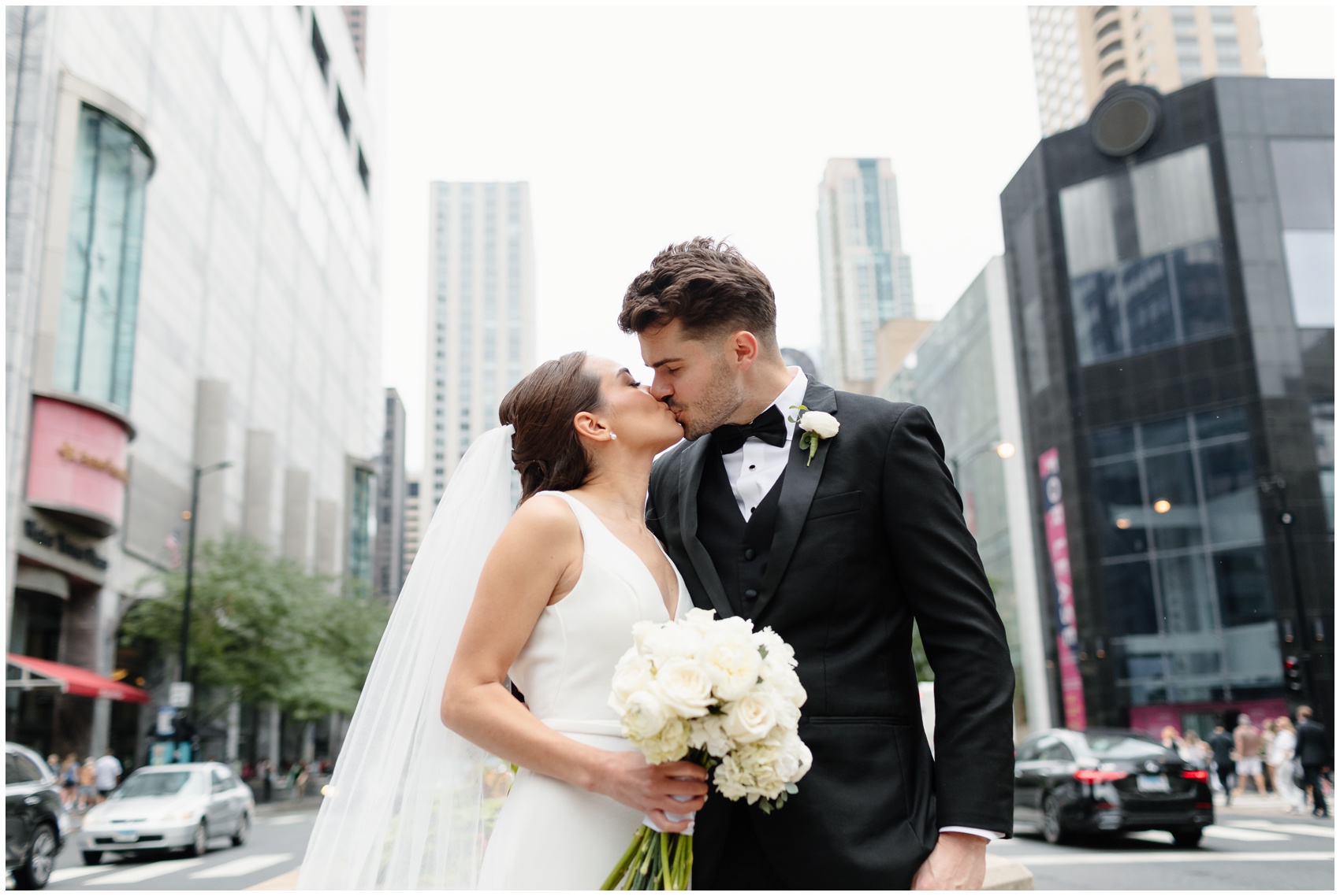 Newlyweds kiss while standing in a downtown street near the arbory chicago