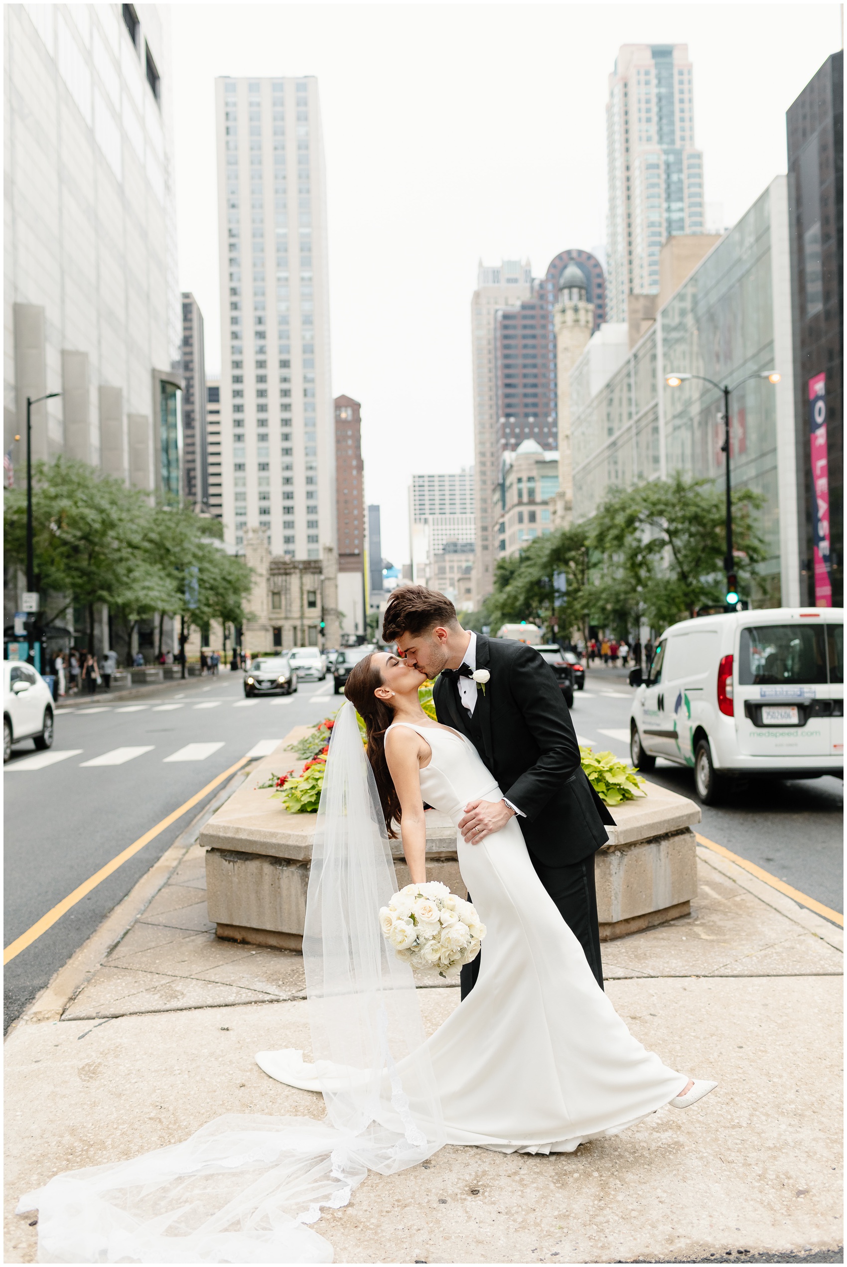 A groom dips and kisses his bride in a median in downtown by the arbory chicago