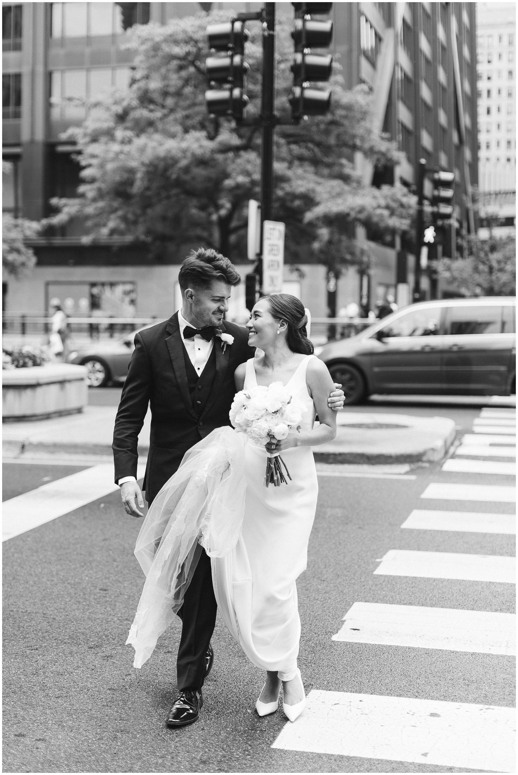 Newlyweds smile at each other while walking on a crosswalk to the arbory chicago