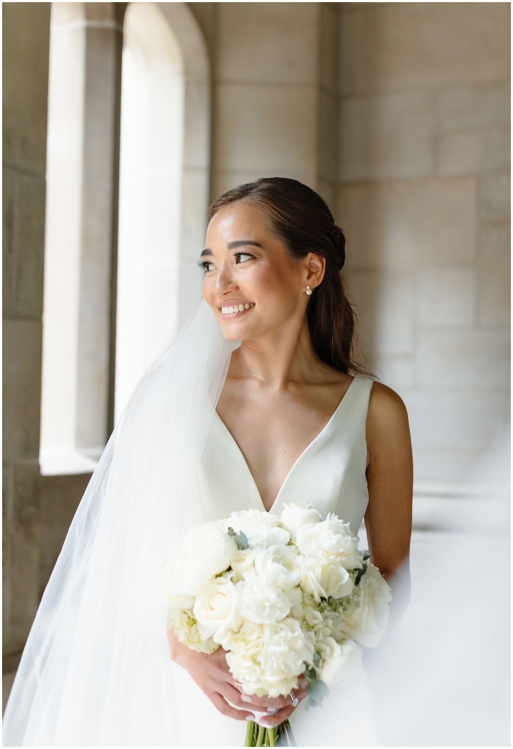 A bride smiles over her shoulder while holding her bouquet