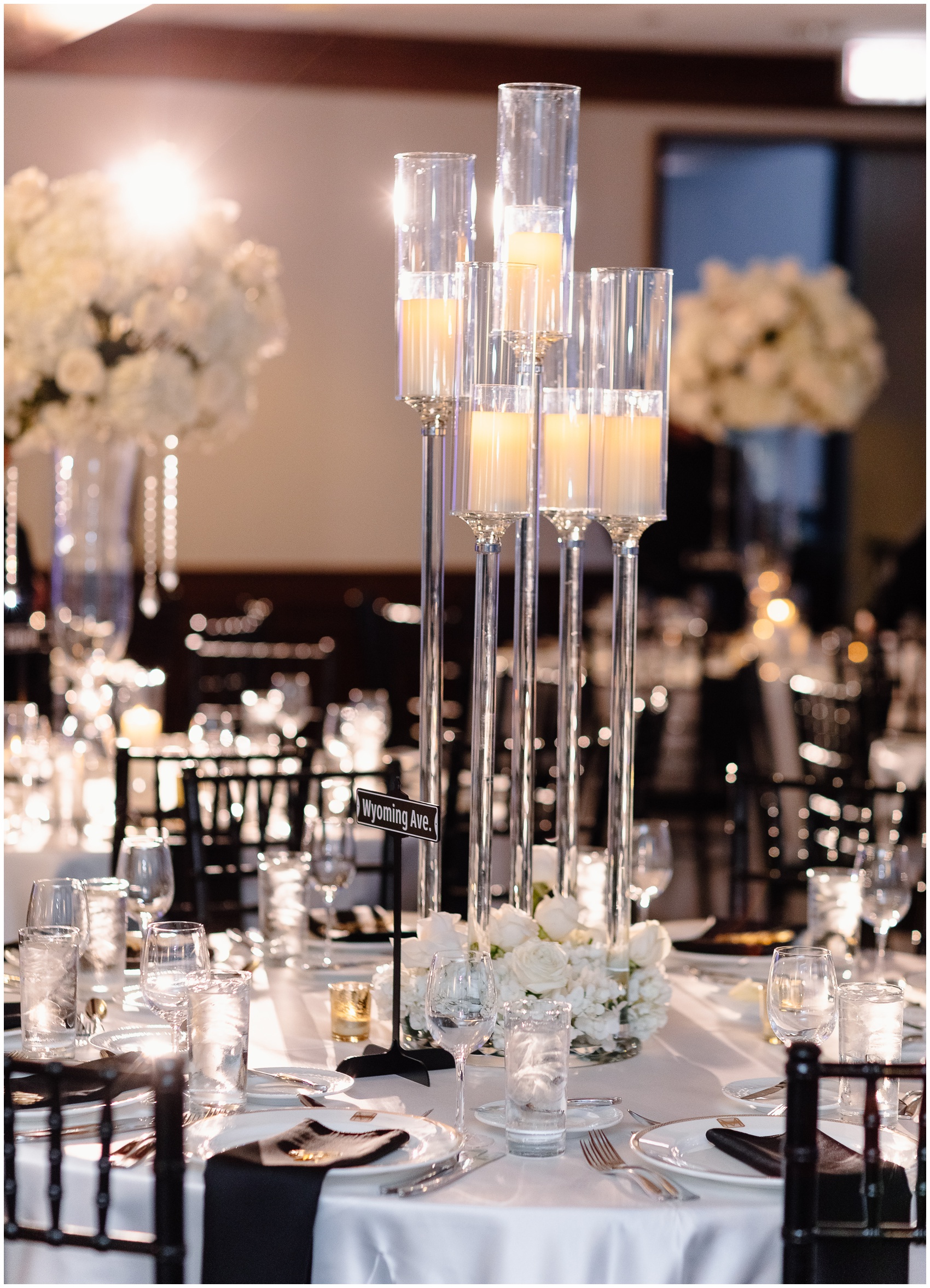 A tall candle centerpiece on white linen tables designed by Chicago Wedding Planners