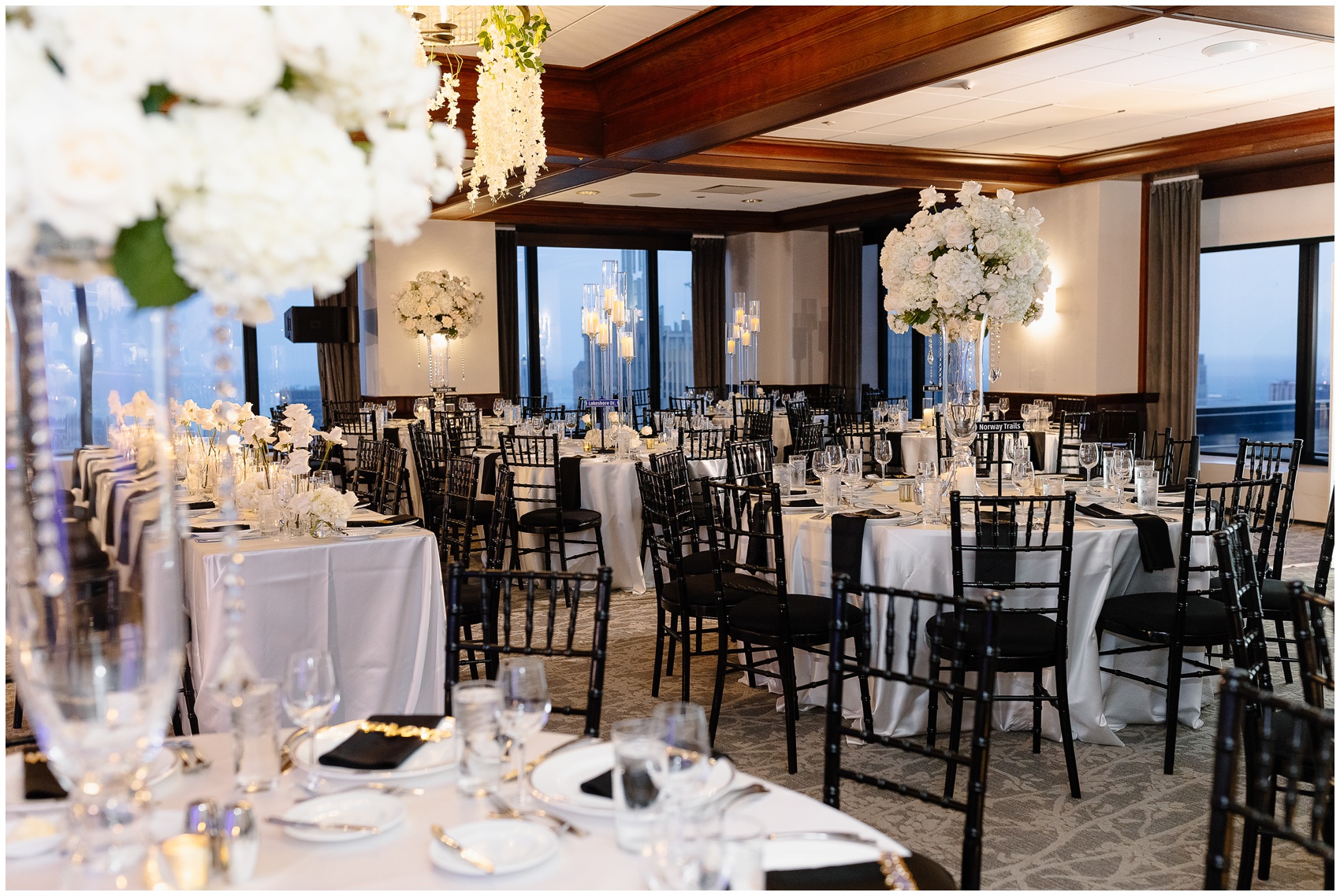 Details of a wedding reception set up with white linens on round tables with black chairs done by Chicago Wedding Planners