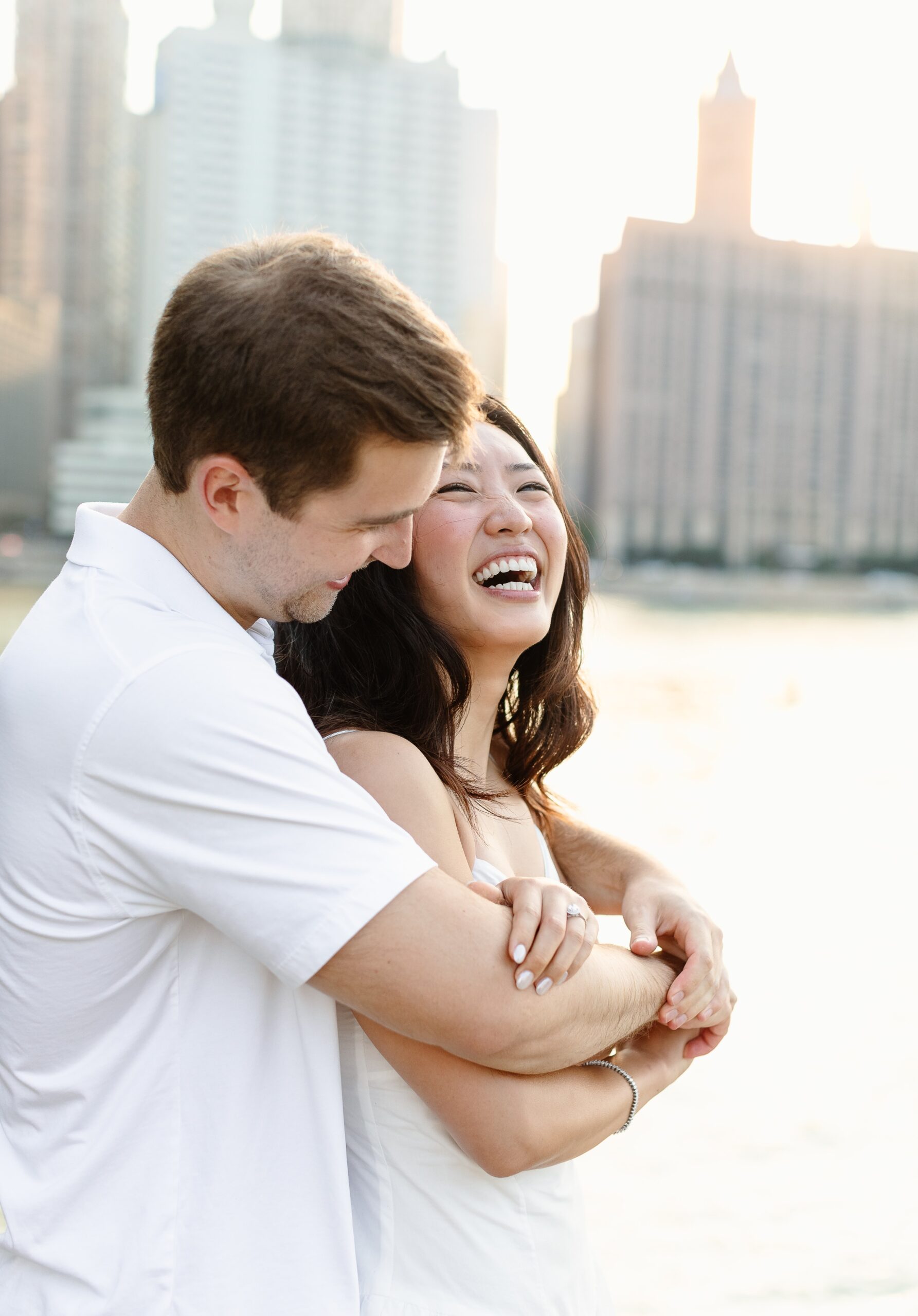 A happy couple laughs while hugging near the water at one of the fantastic engagement photo locations chicago at sunset