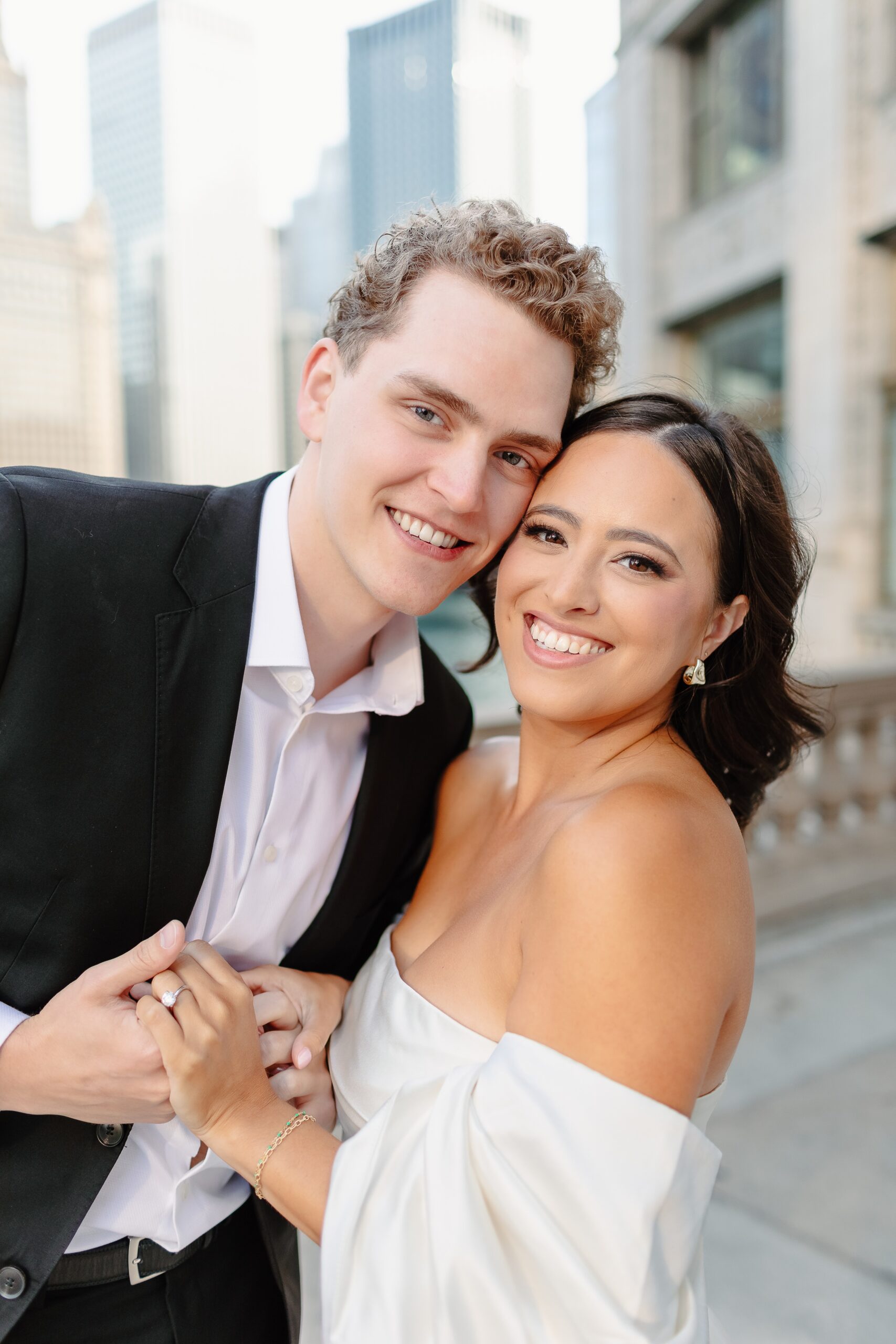 A happy couple smiles while cheek to cheek on a balcony