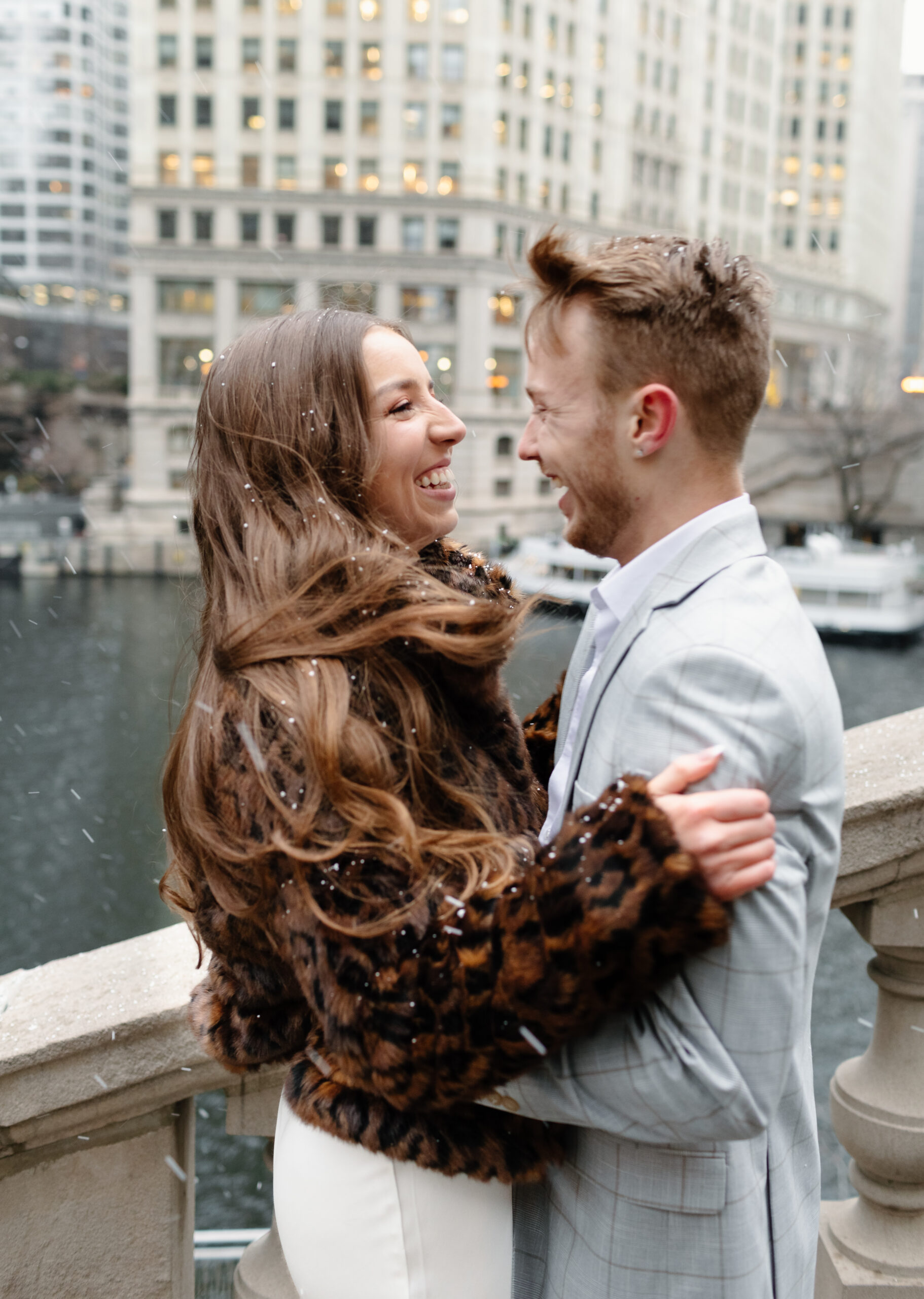 couple laughs at each other as it snows in chicago