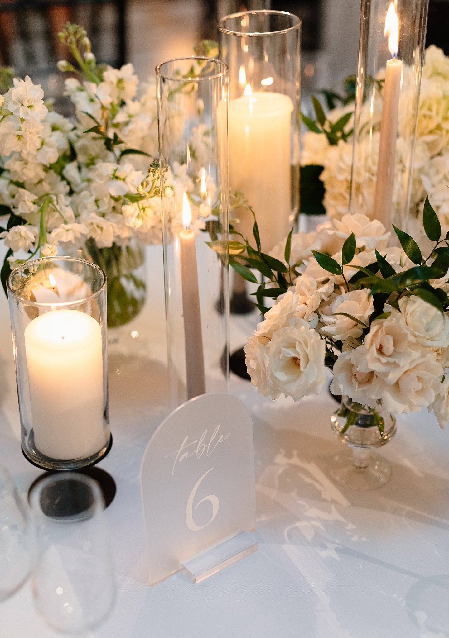 Details of a table sign on a reception table with white linen, white flowers and candles