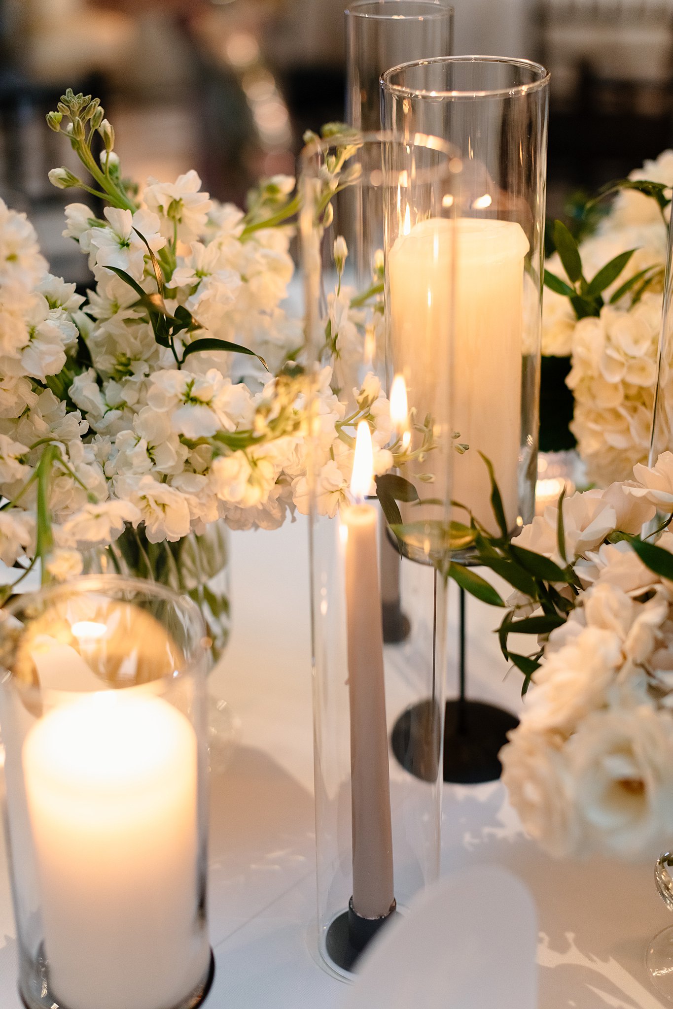 Details of candles in a centerpiece of a reception table with white flowers