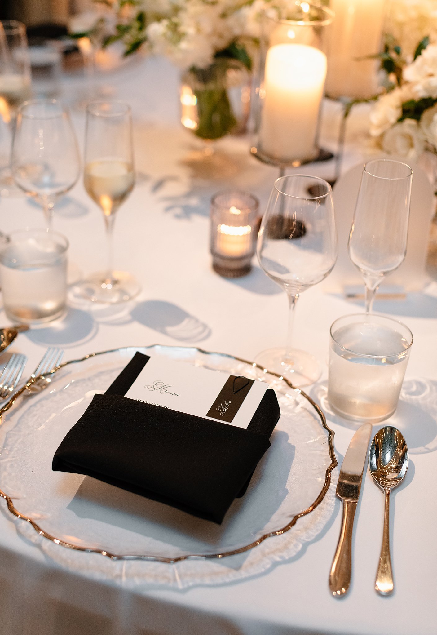 A table setting with a black napkin lit with candles