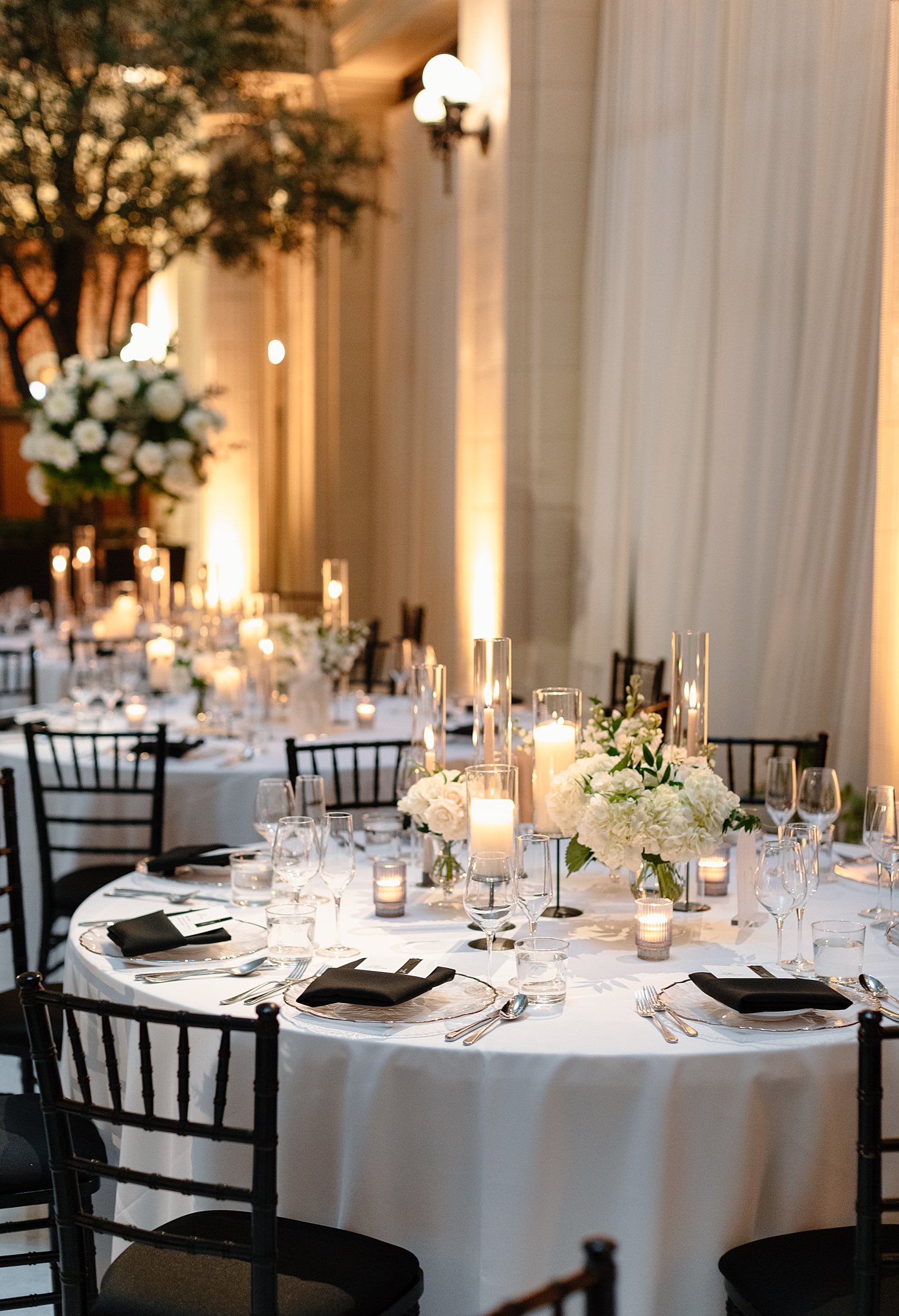 Details of a round reception table setting with white roses and candles centerpiece at one of the Downtown Chicago Wedding Venues