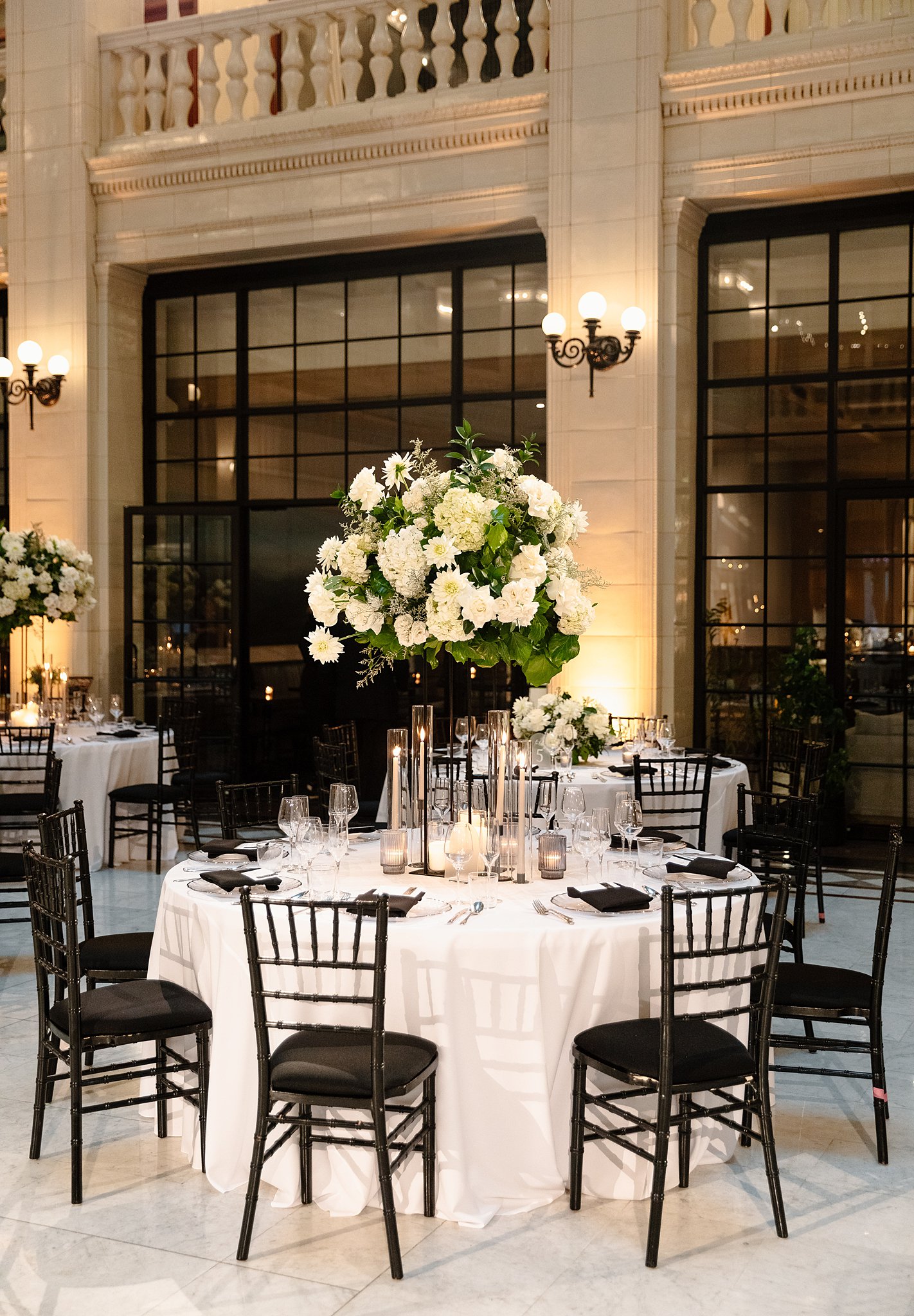 A Downtown Chicago Wedding Venue reception table set up with white linen, black chairs and extra large floral centerpiece