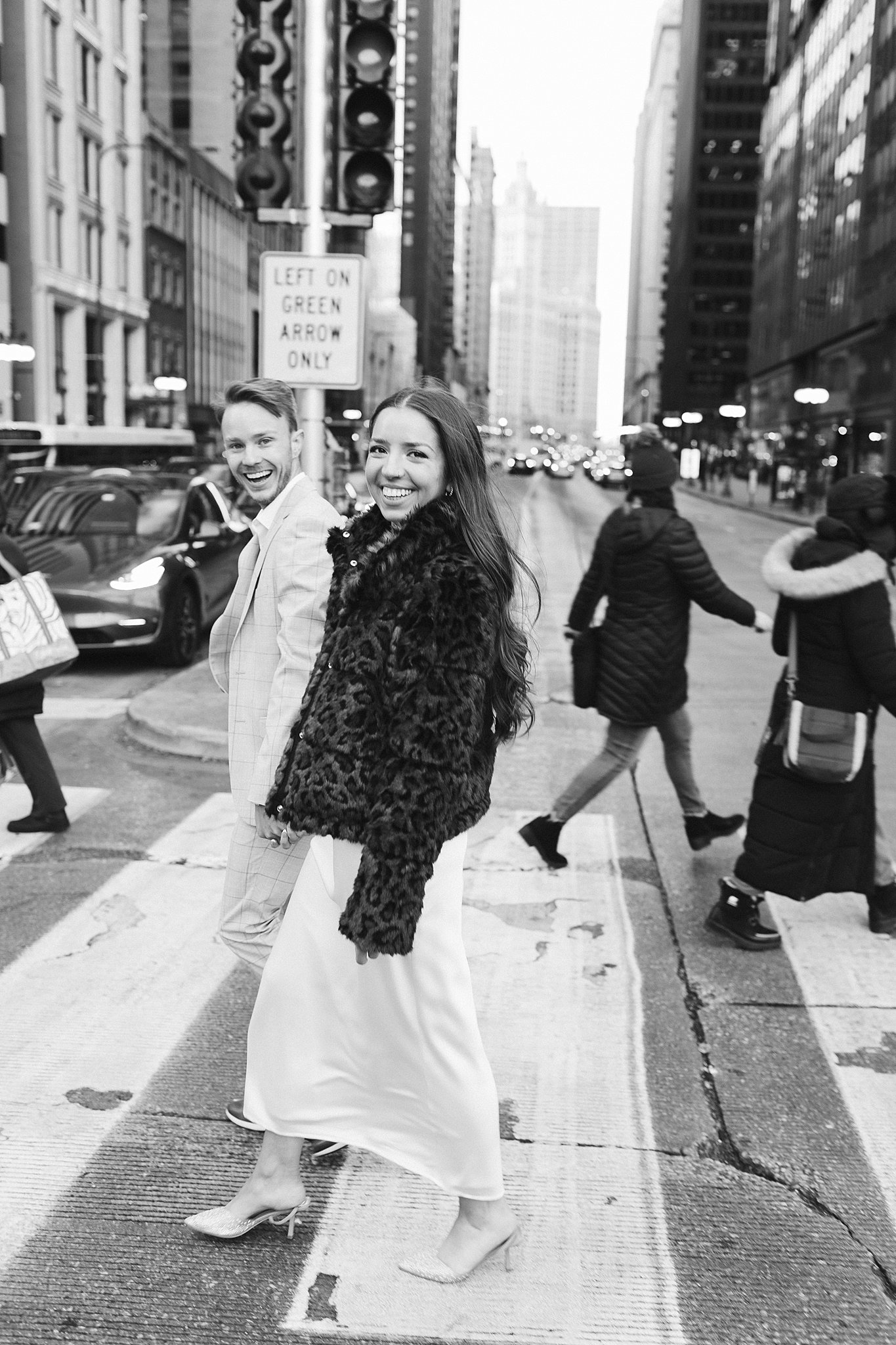 A happy couple laughs while crossing the street holding hands