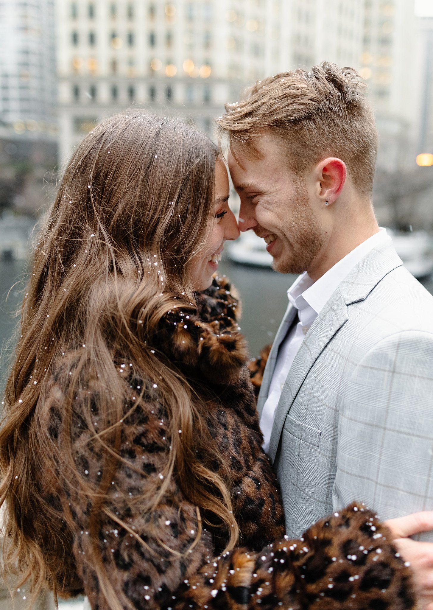 An engaged couple touches noses while smiling in the snow during their winter engagement photos in chicago