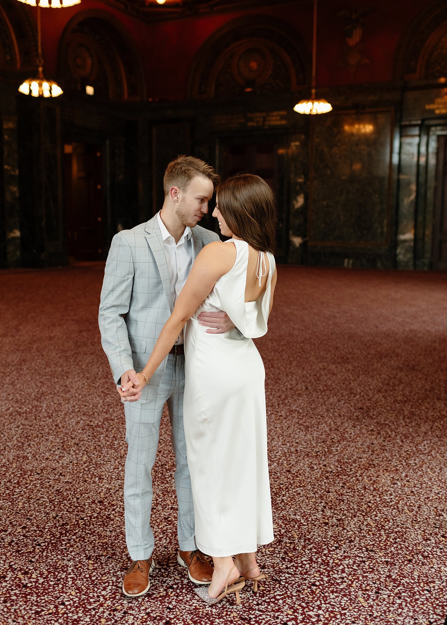 A happy couple dances and snuggles in a large lobby